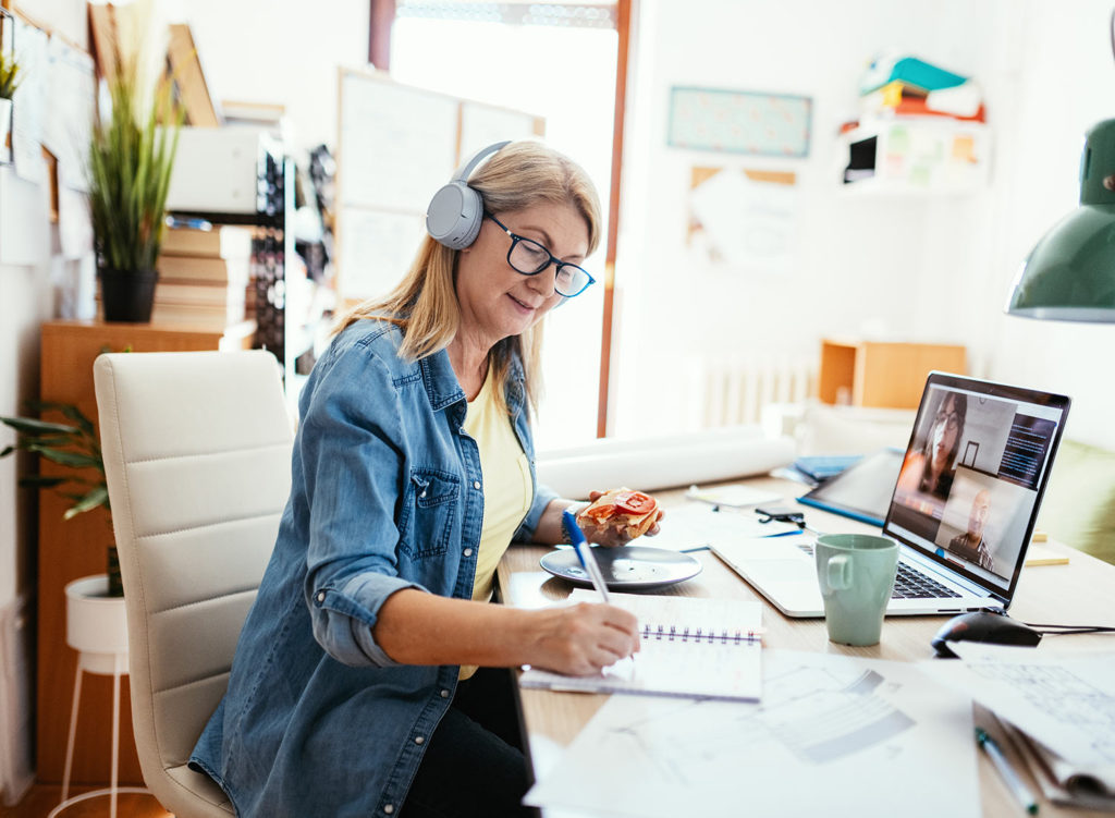 Lady sat at desk on call writing a note