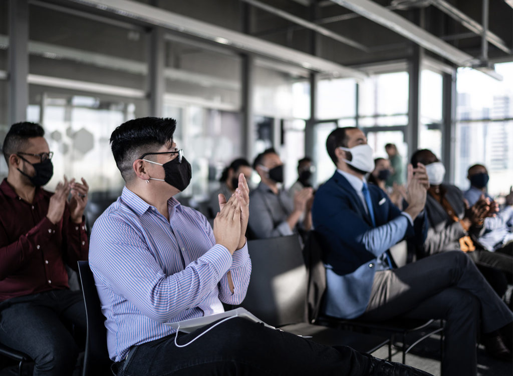 conference audience all clapping wearing masks and socially distanced