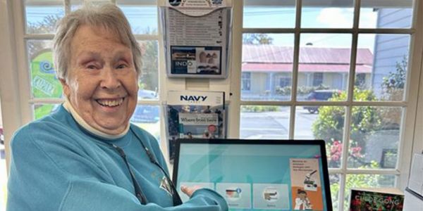 A smiling patron using the selfCheck™ kiosk at Kaipara District Libraries, NZ, enjoying the convenience of self-service checkout.