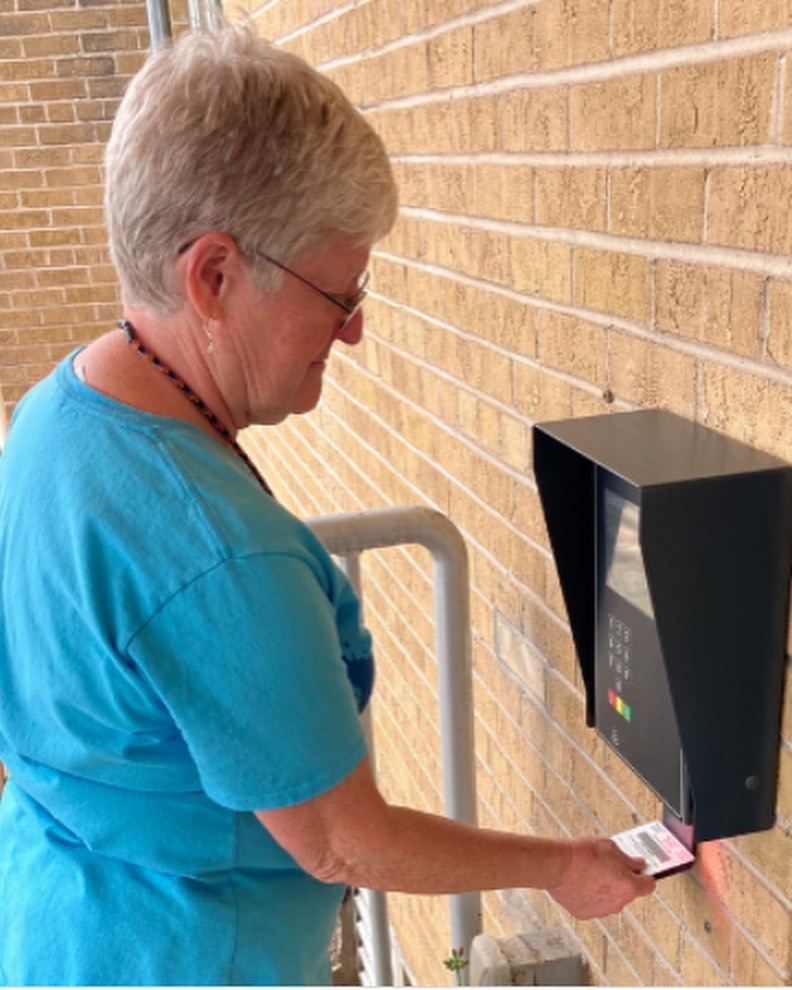 Elderly woman using her library card to access Summit County Library's open+ system at the entrance.