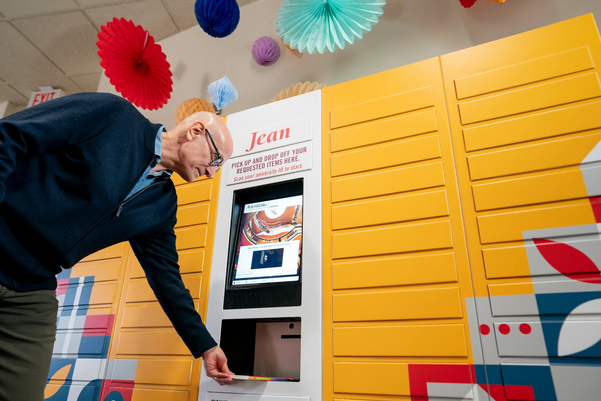 A person returns a book through the Jean remoteLocker system at Augsburg University’s Lindell Library, highlighting convenient self-service access for students.